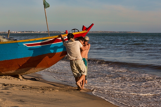 Putting the fishing boat into the water at the Beach in Hàm Tiến